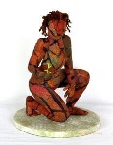 A sculptural textile artwork depicts a woman with parched, orange and black skin holding a small green sprout.