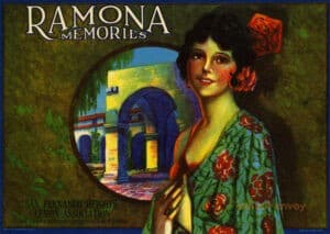 On an old advertising label, there is an illustration of a woman with a flower in her hair, hoop earrings, and a floral shawl in the foreground. The background shows part of a mission. The label is for the San Fernando Heights Lemon Association and has a title of Ramona Memories.