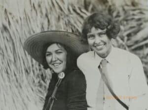 Two smiling women look at the camera while outside.