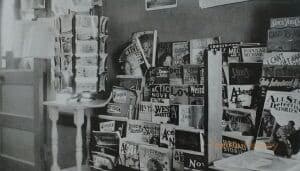 Interior of a post office with a postcard rack and magazine rack.